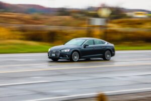 A black sports car driving along a countryside road