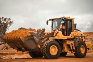 A yellow excavator hauling earth.